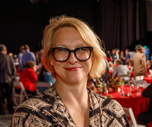 Potrait of a woman with short blonde hair and black glasses.